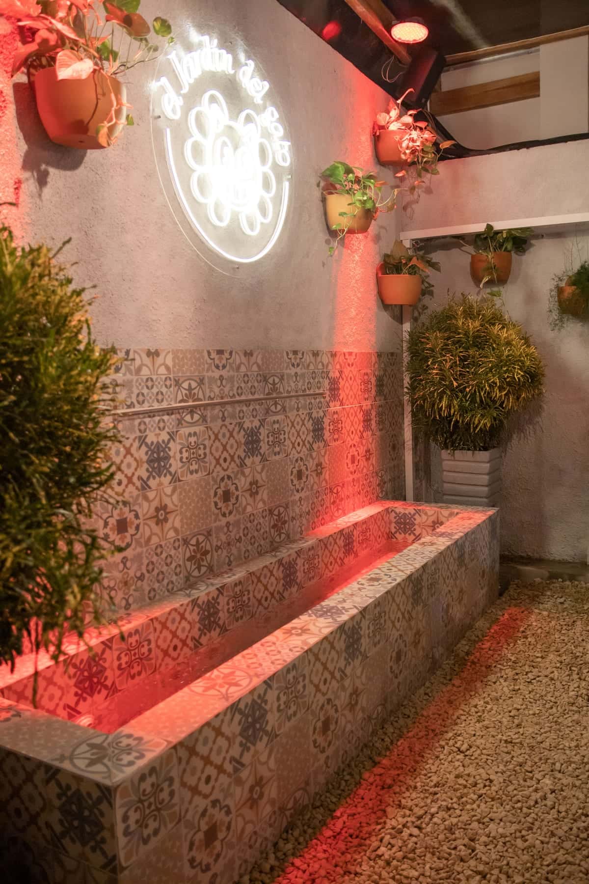 The patterned tiles at the foot of the wall, under the neon sign and the red light