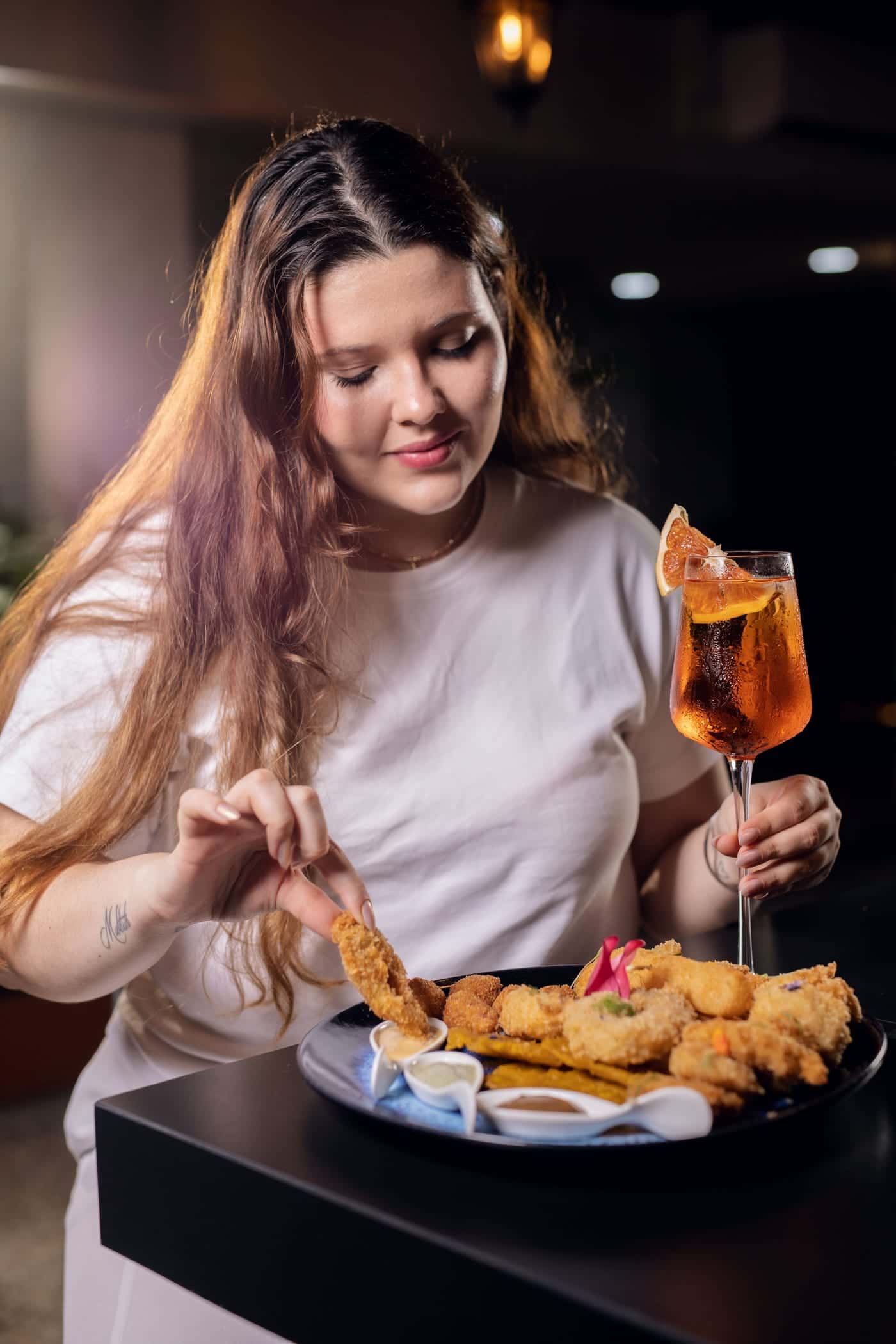 A guest takes a bite of the Picada Marejada, with a spritz beside her