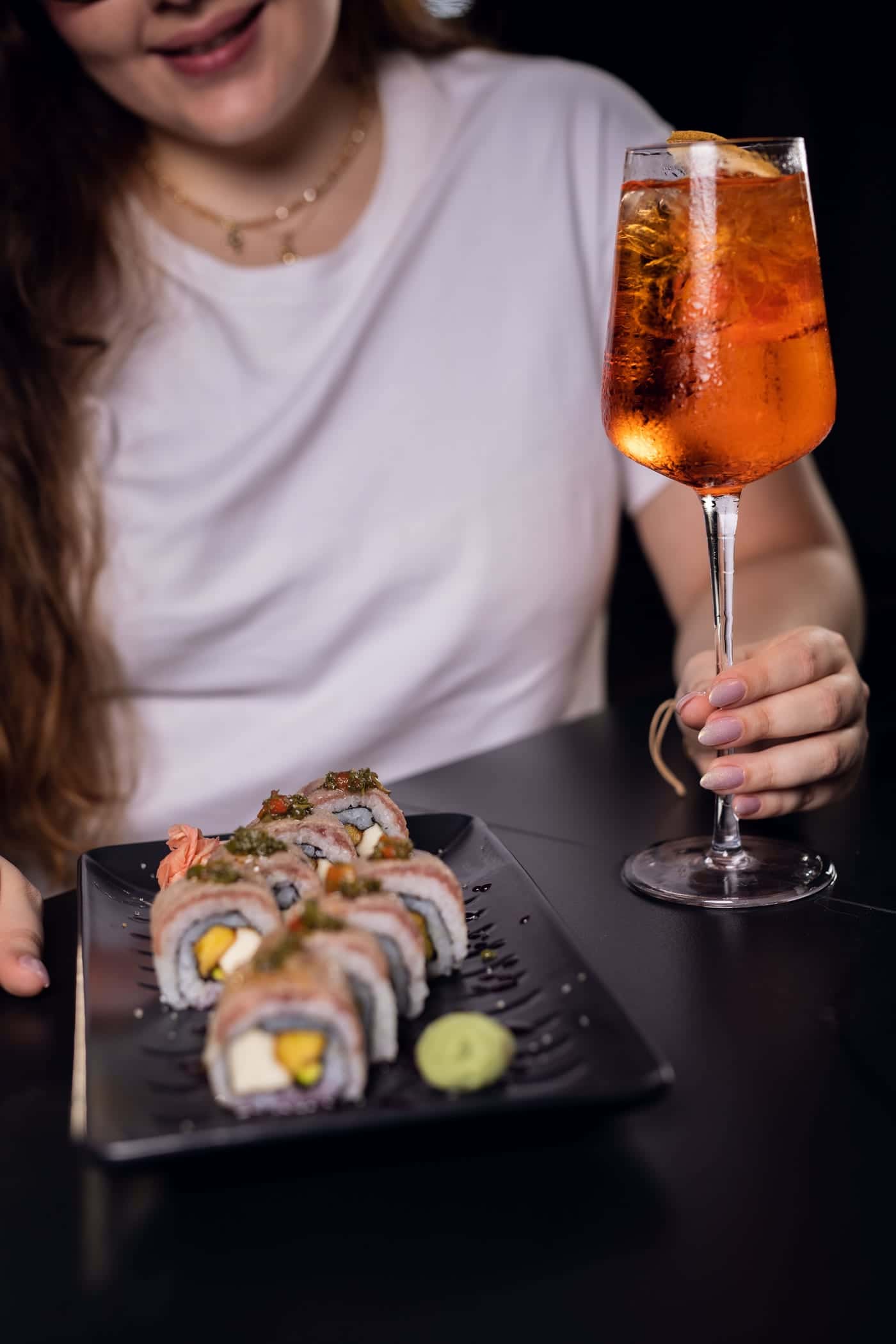 A spritz in hand, beside a plate of Rib Eye Roll