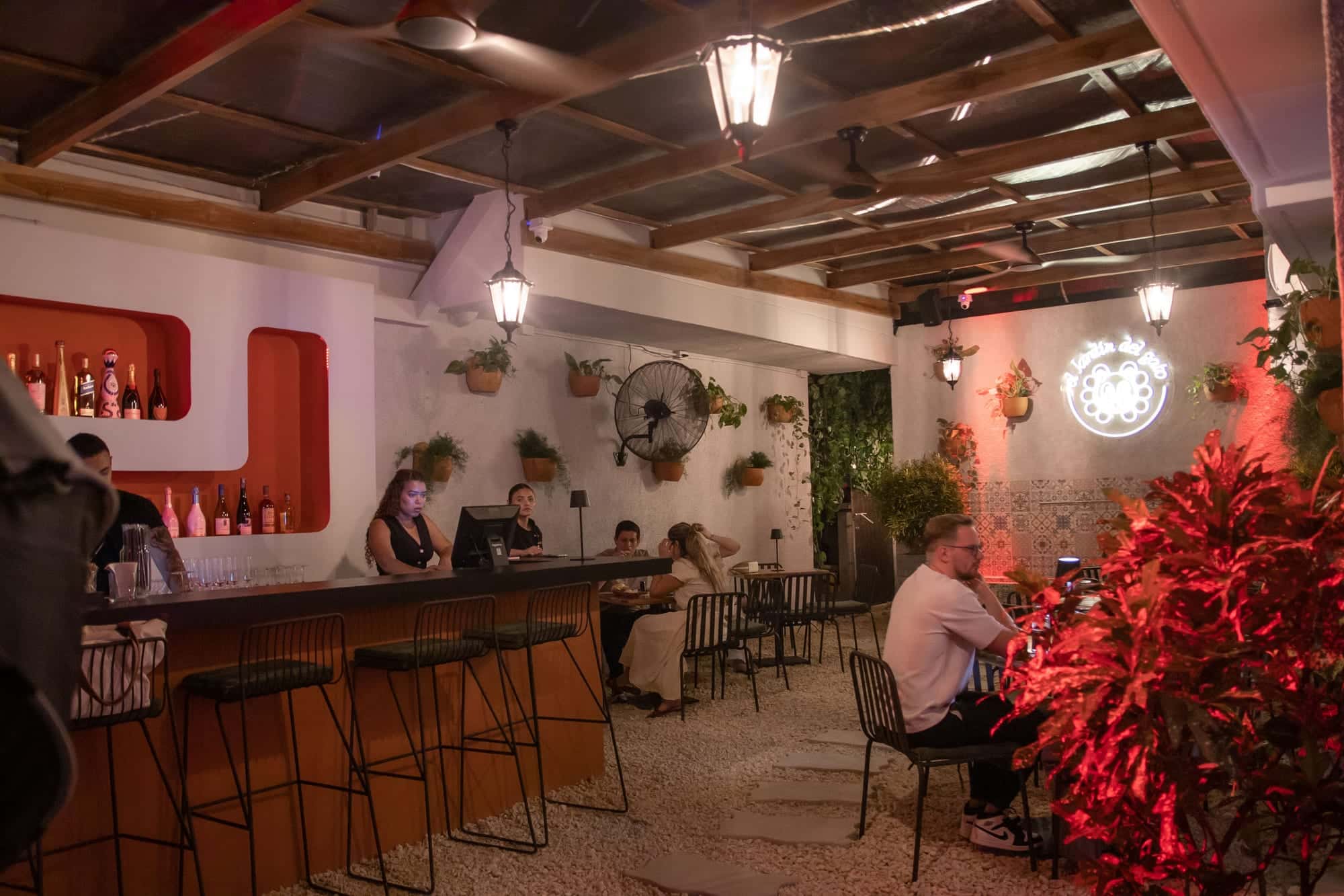 The patio at night: the bar, full tables and the cat sign at the back